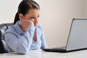 a woman looking at a laptop thinking If It’s Too Good to Be True it probably is